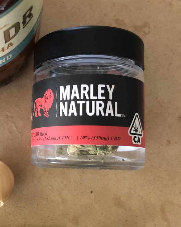 a jar of marley natural cbd-rich flower beside a kombucha and a clove of garlic, california, august 2019