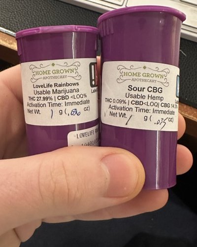 two labeled vials in hand: lovelife rainbows thc flower and sour cbg hemp flower